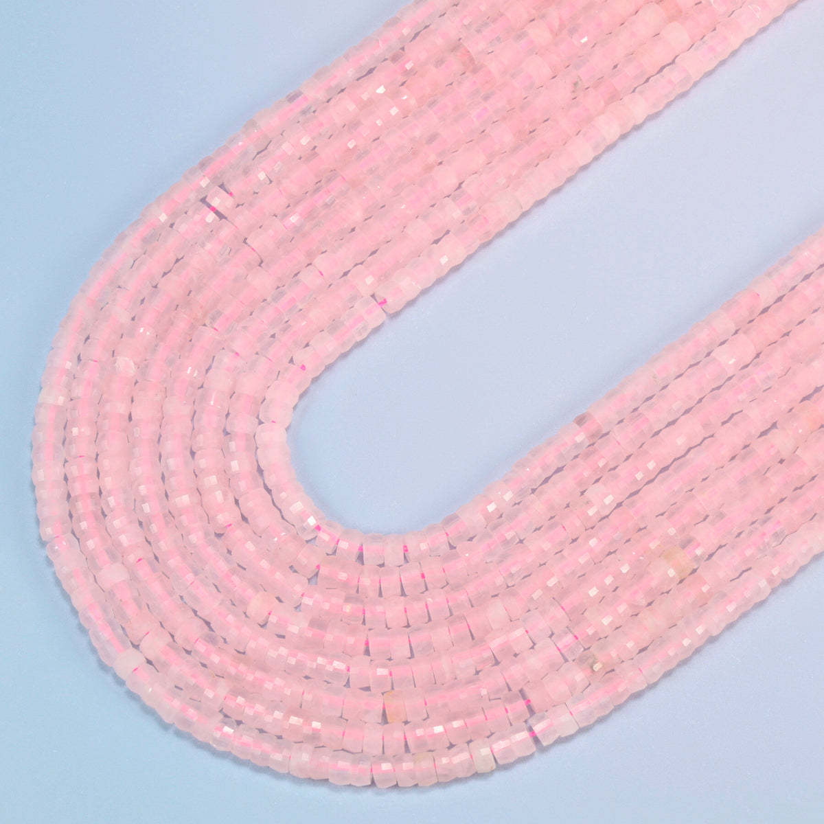 Rose quartz faceted heishi disc beads in several strands curved into a wide U, soft translucent pink stone