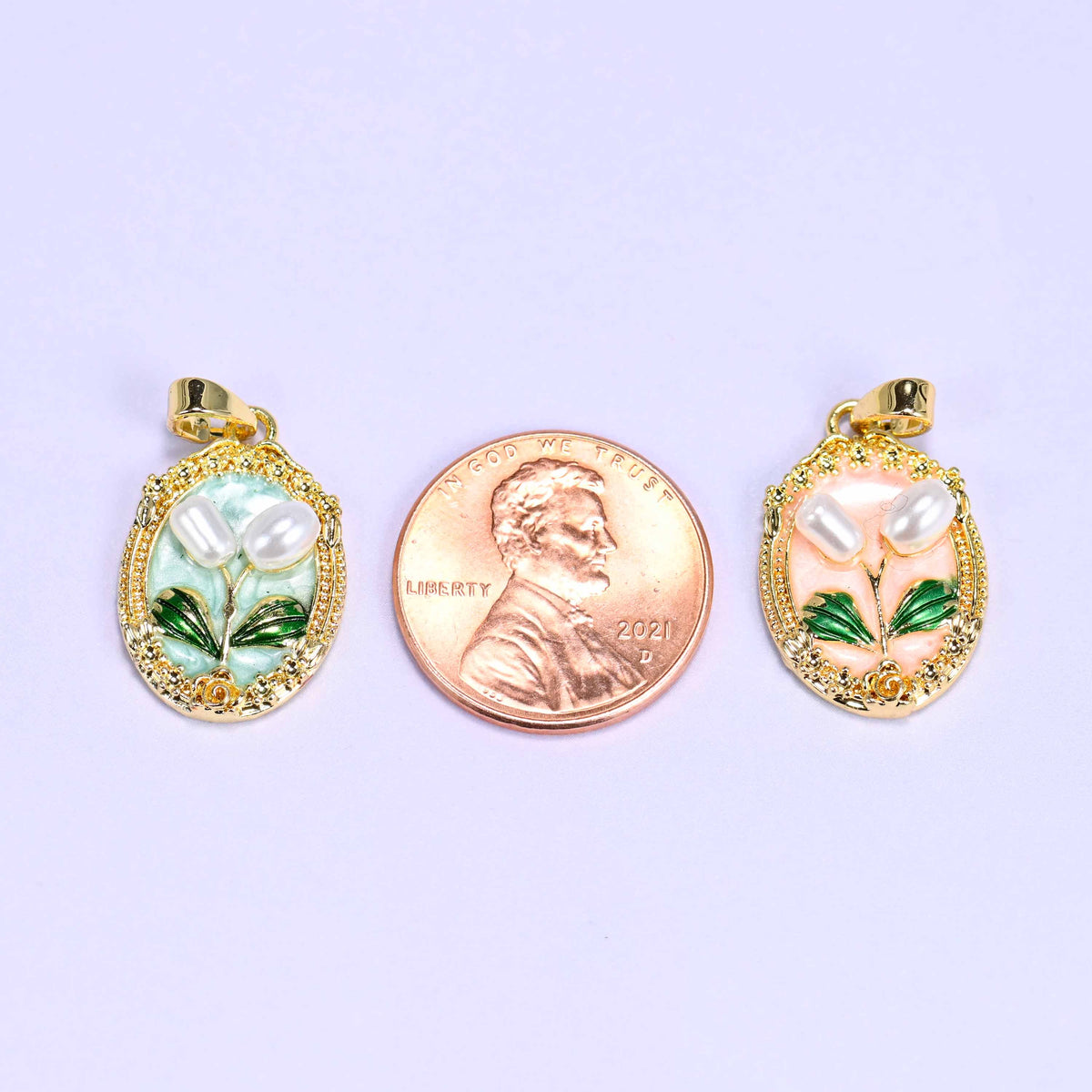 Enamel Oval Tulip Flower Pendants with a US penny between them for scale, mint on the left and peach on the right at about 20mm tall.
