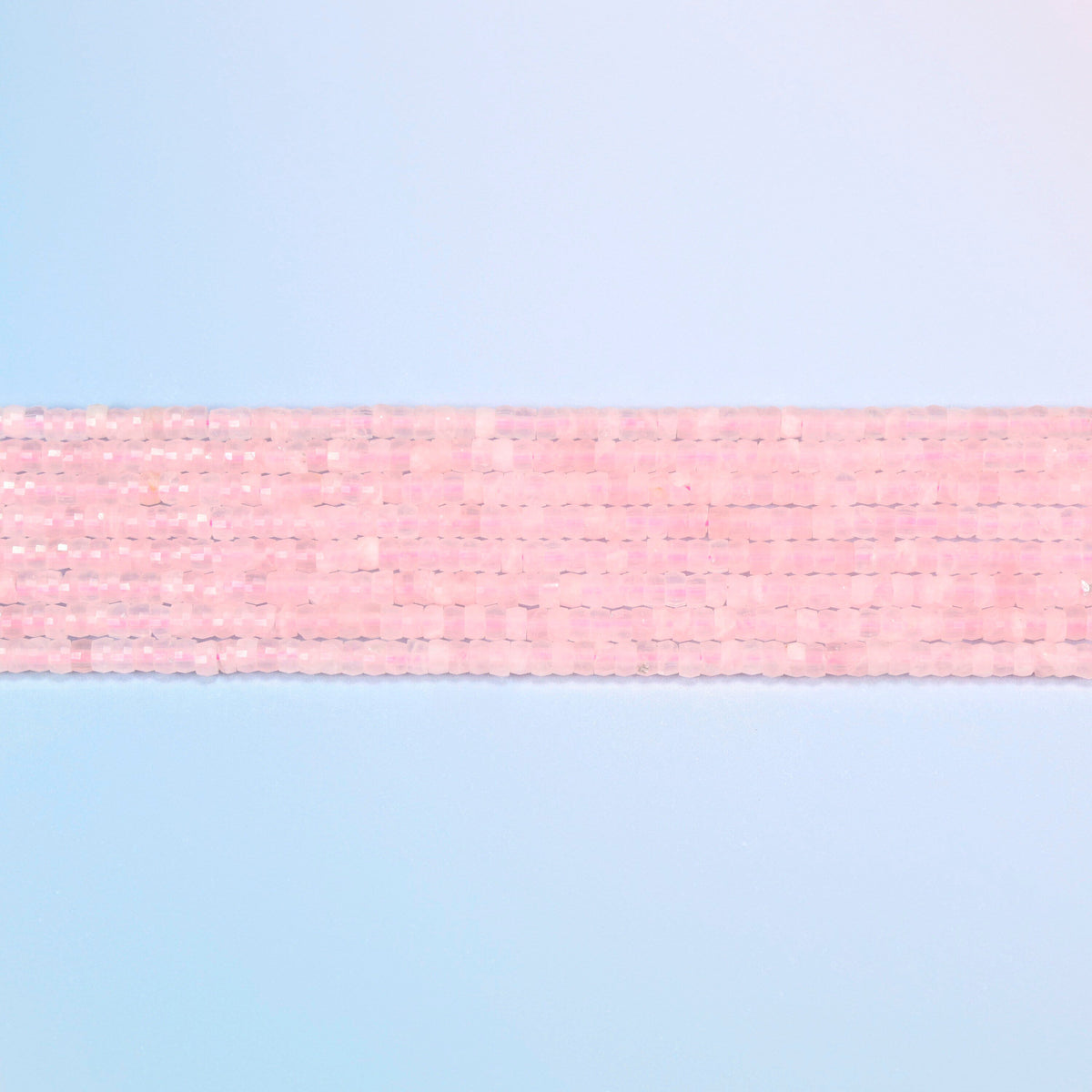 Several strands of rose quartz faceted heishi disc beads laid in straight rows