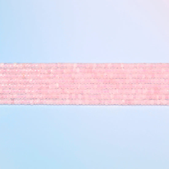 Several strands of rose quartz faceted heishi disc beads laid in straight rows