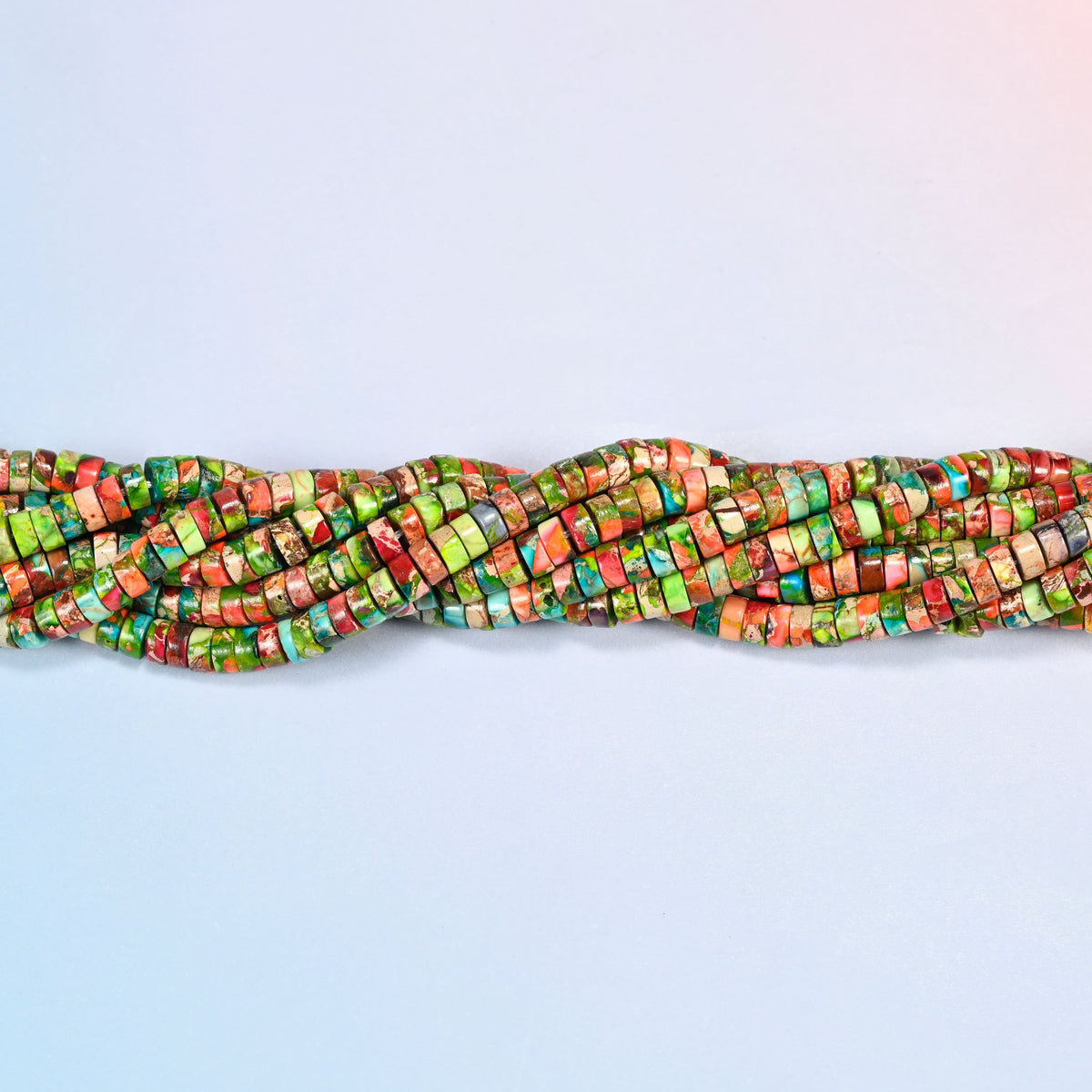 Strands of dyed blue green sea sediment jasper heishi disc beads 2x4mm twisted together in a horizontal row