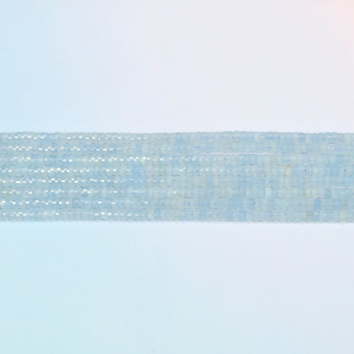 Several strands of aquamarine chalcedony faceted heishi disc beads laid in straight rows