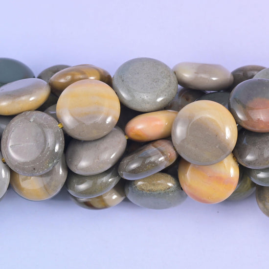 Close macro of stacked picture jasper coins, honey and cream banding crossing the grey stone