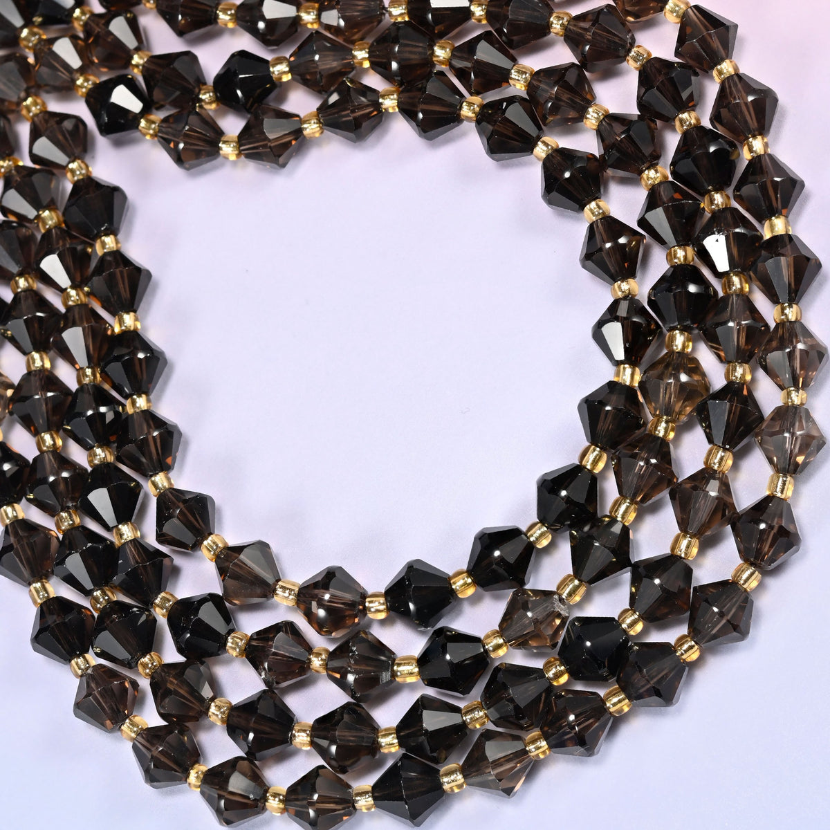 Close-up of 8mm Smoky Quartz faceted bicone beads coiled into a circle, showing the faceted cut and translucent brown-gray color.