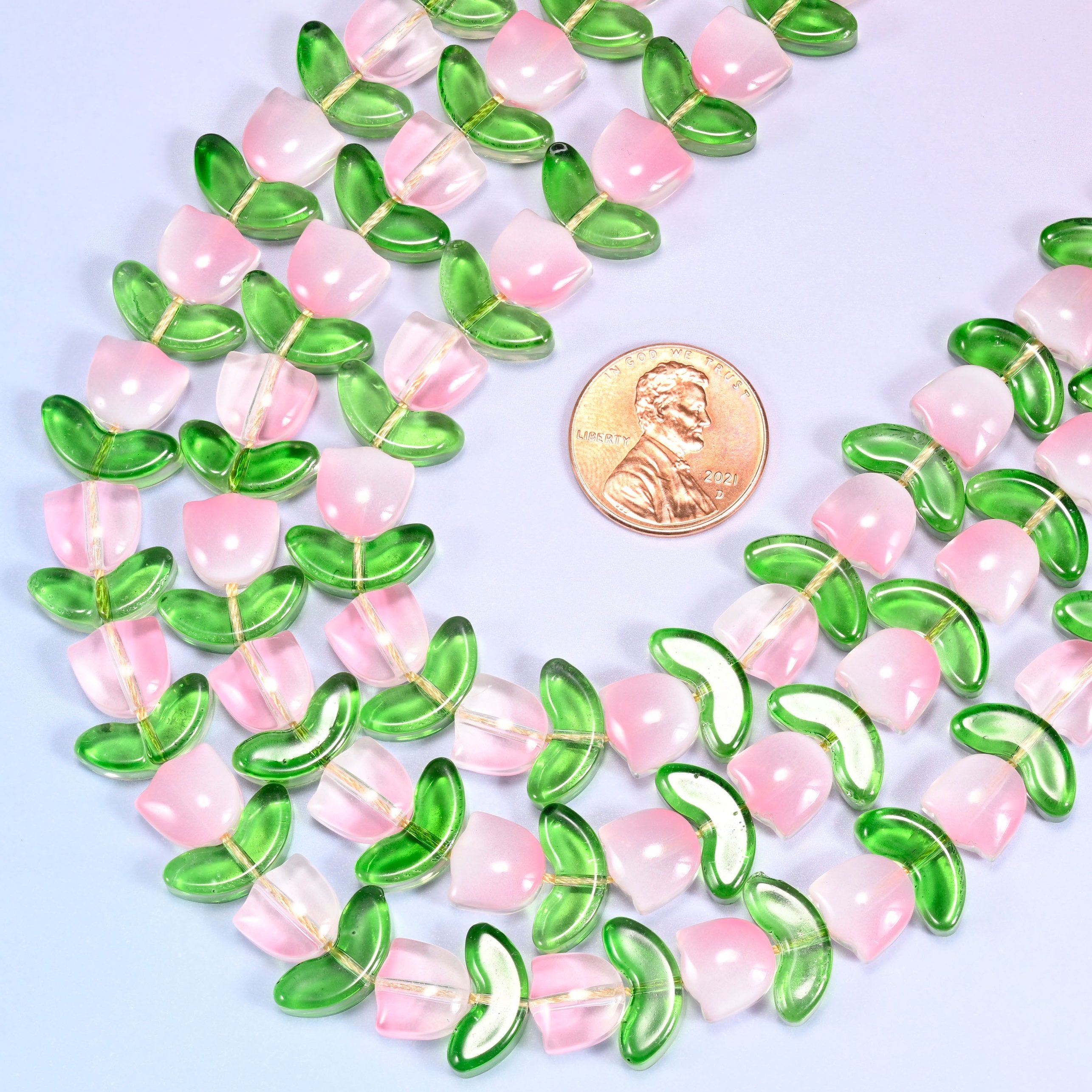 Close-up of a dense circular coil of pink tulip and green leaf glass beads, showing the alternating flower and leaf pattern.