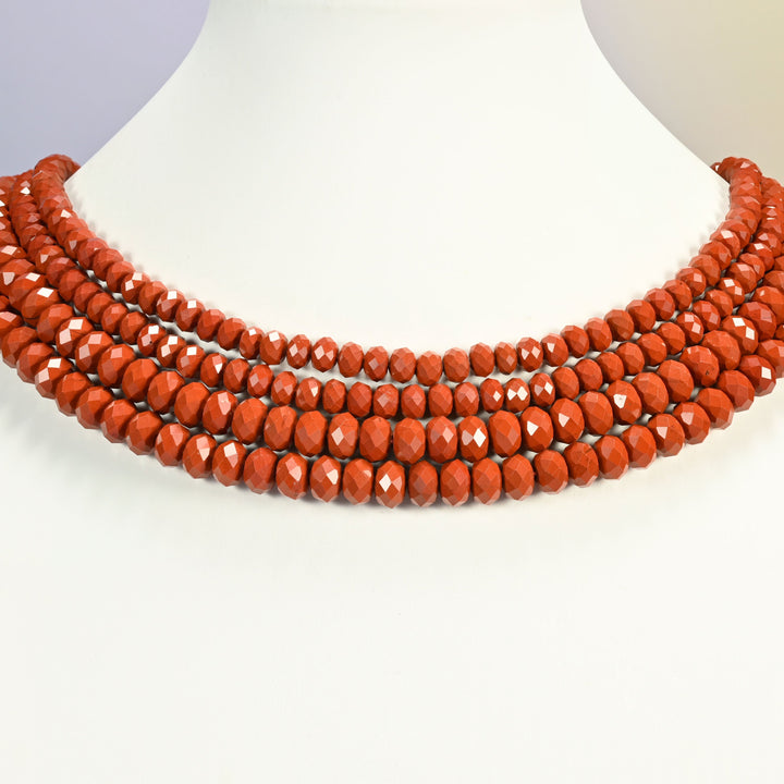 Red jasper beads shown on a white neck display bust, the faceted rondelle strands sitting in even rows against the curve of the neck