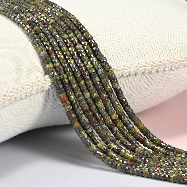 Dragon blood stone faceted heishi disc beads 2x4mm, several strands draped over a white cushion