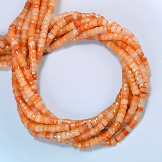 Red aventurine faceted heishi disc beads coiled into overlapping loops, whole strands of warm orange-red stone