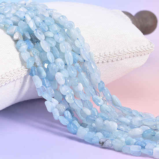 Pale ice-blue aquamarine nugget bead strands draped over a white cushion