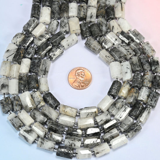 Black rutilated quartz faceted tube strands formed into a teardrop loop around a US penny for scale