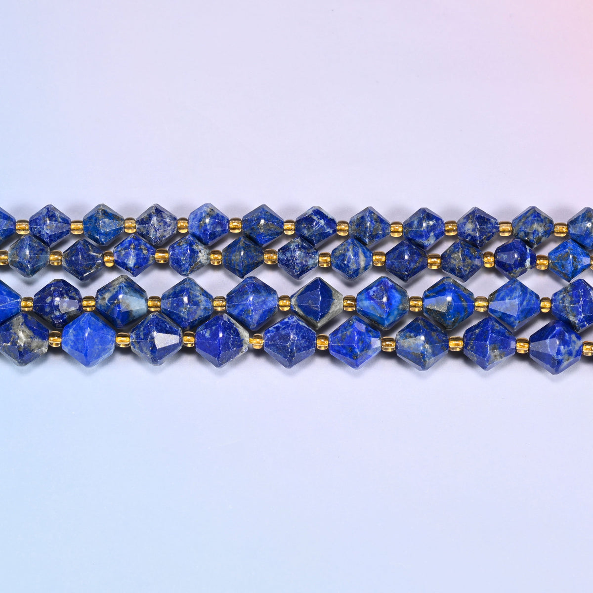 Lapis lazuli bicone beads in straight rows, seen close up, each bead cut to two points meeting at a wide center.