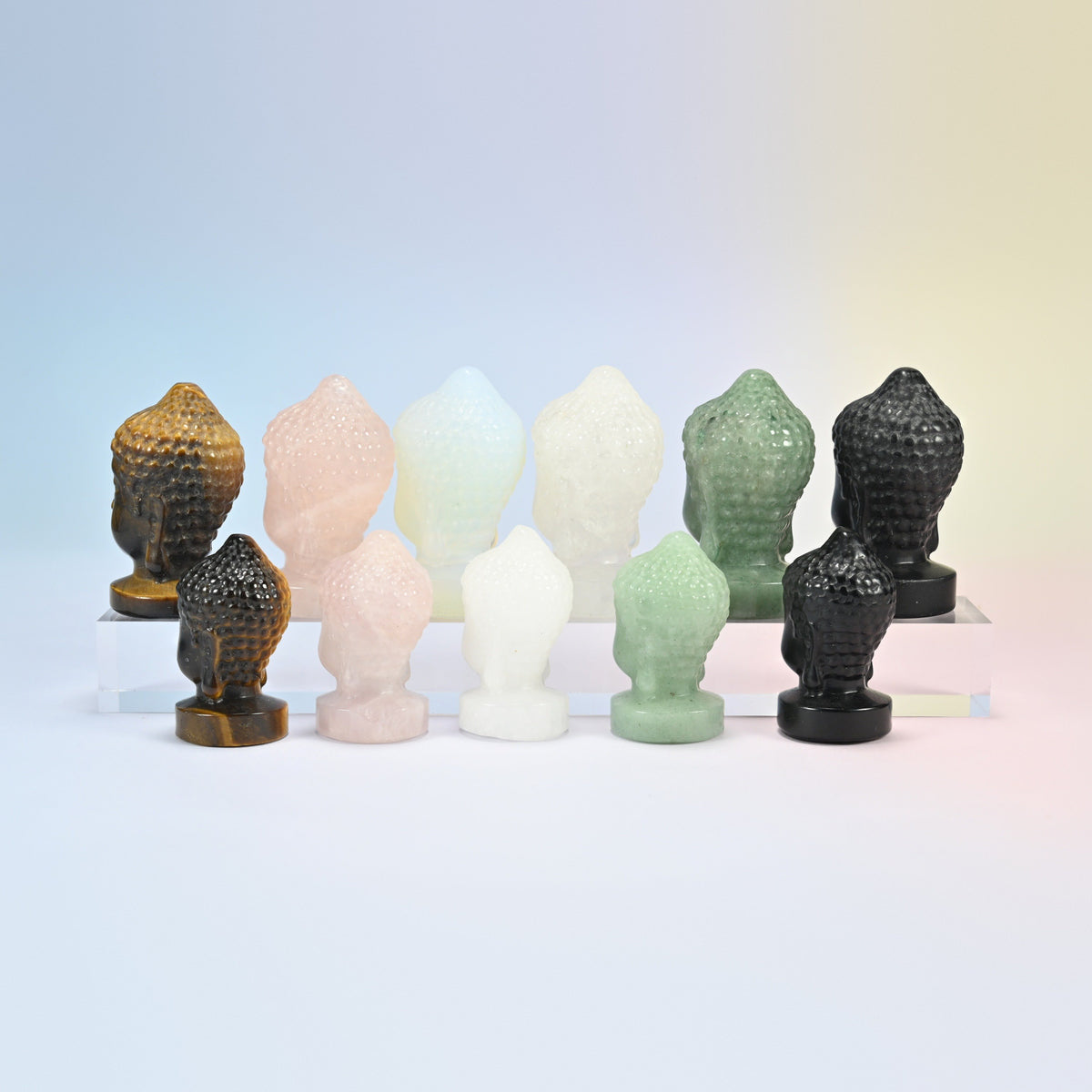 Buddha head carvings at an angle in tiger eye, rose quartz, opalite, clear quartz, green aventurine and black obsidian