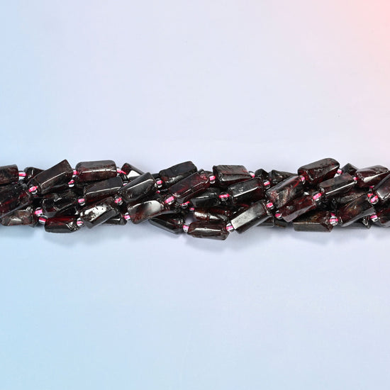 Strands of red garnet tube beads twisted together in a horizontal row