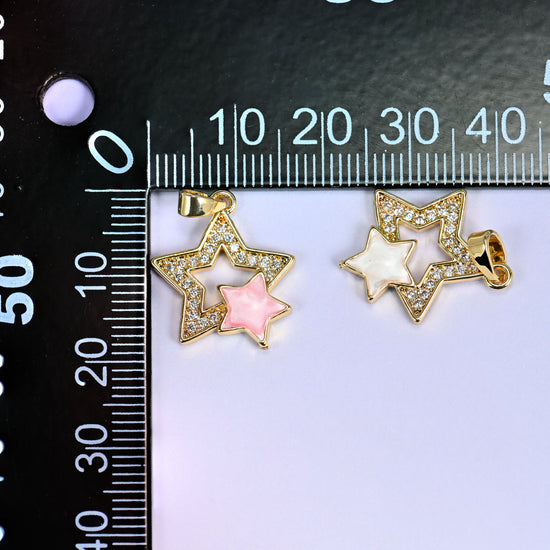 Both Double Stars Zirconia Charms colorways on a black millimeter ruler, pink and white shell pendants shown together against the mm scale.