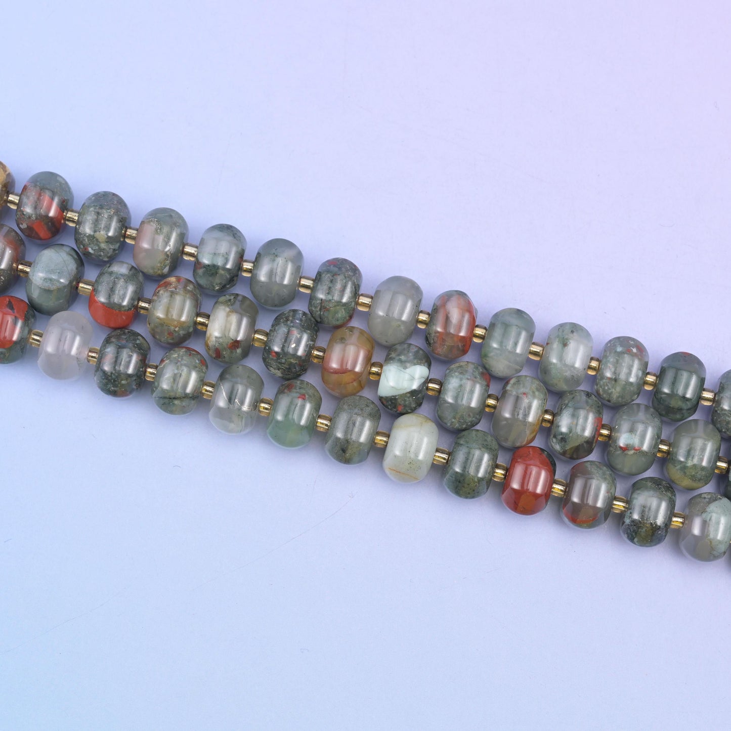 Angled run of 12x8mm pumpkin rondelles across pale lilac, gold seed beads between each stone