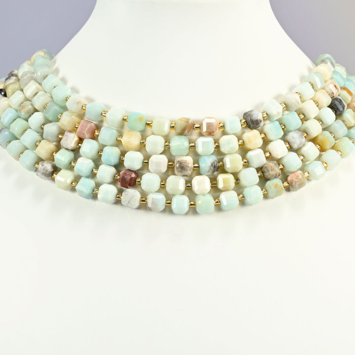 Multi-color amazonite faceted cube strands arranged as a layered collar on a white display bust, light blue and cream beads across the neck
