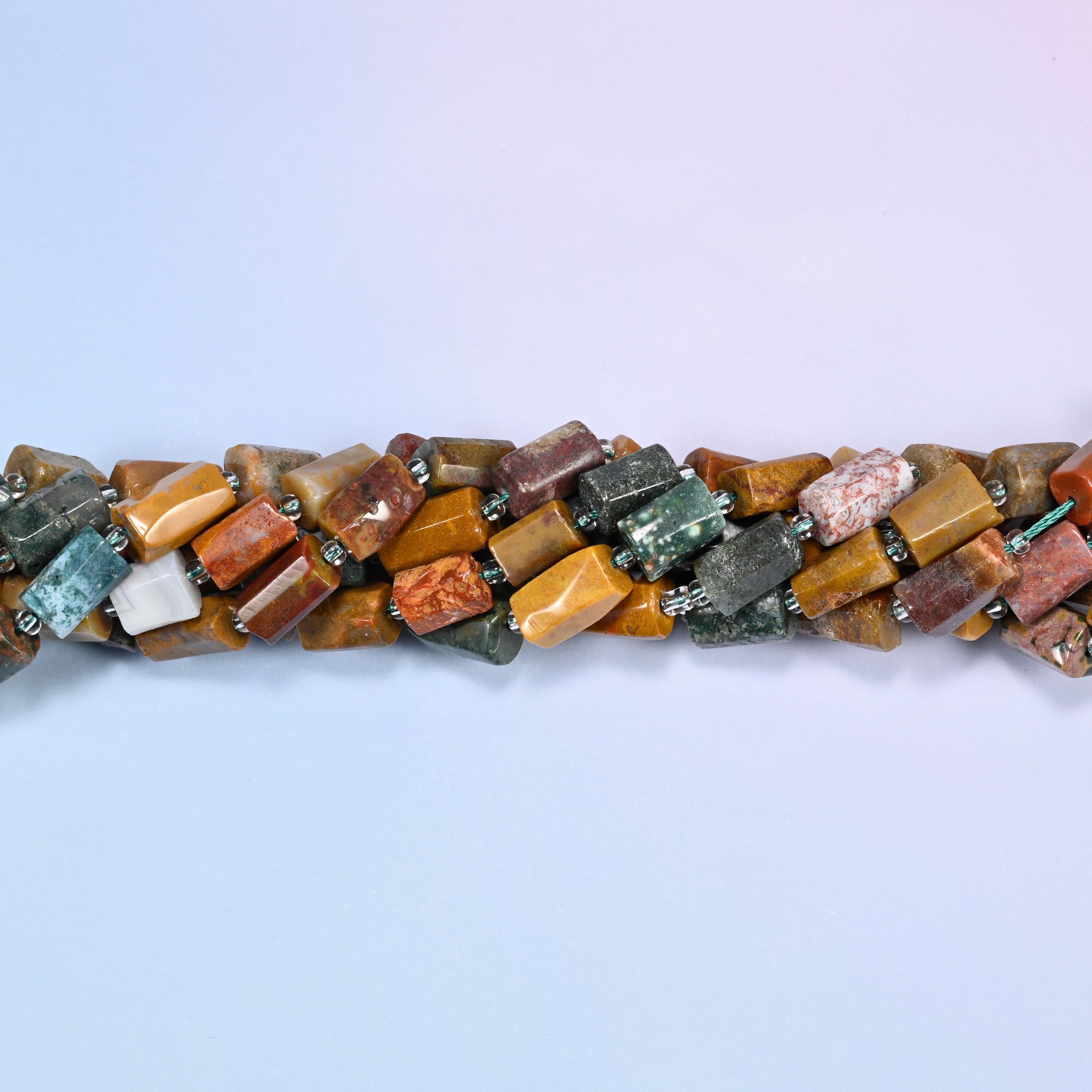 Close-up of coiled Ocean Jasper tube beads with clear glass spacers, showing the natural stone texture and color variation.