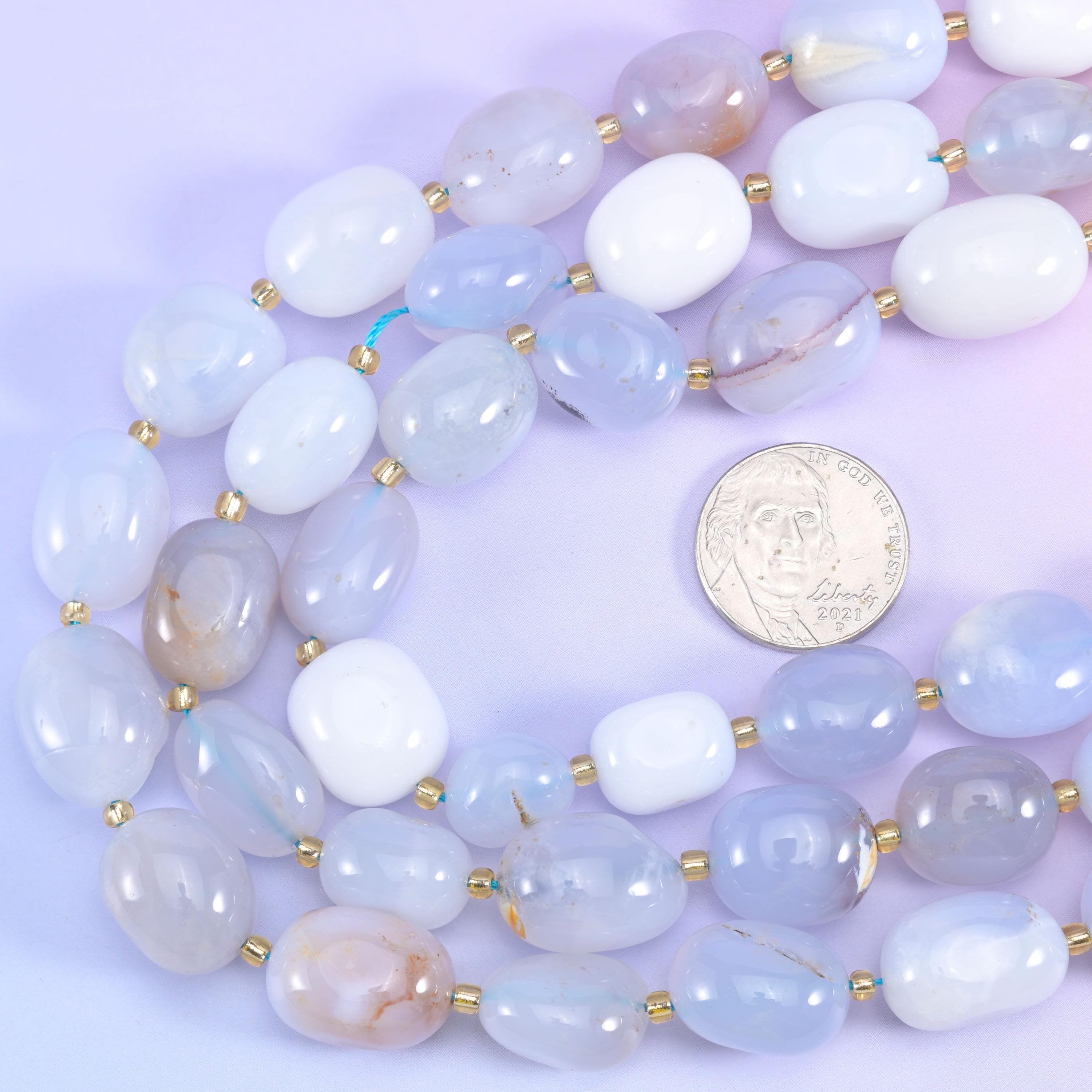 US quarter set beside coiled chalcedony nugget strands to show the range of bead sizes