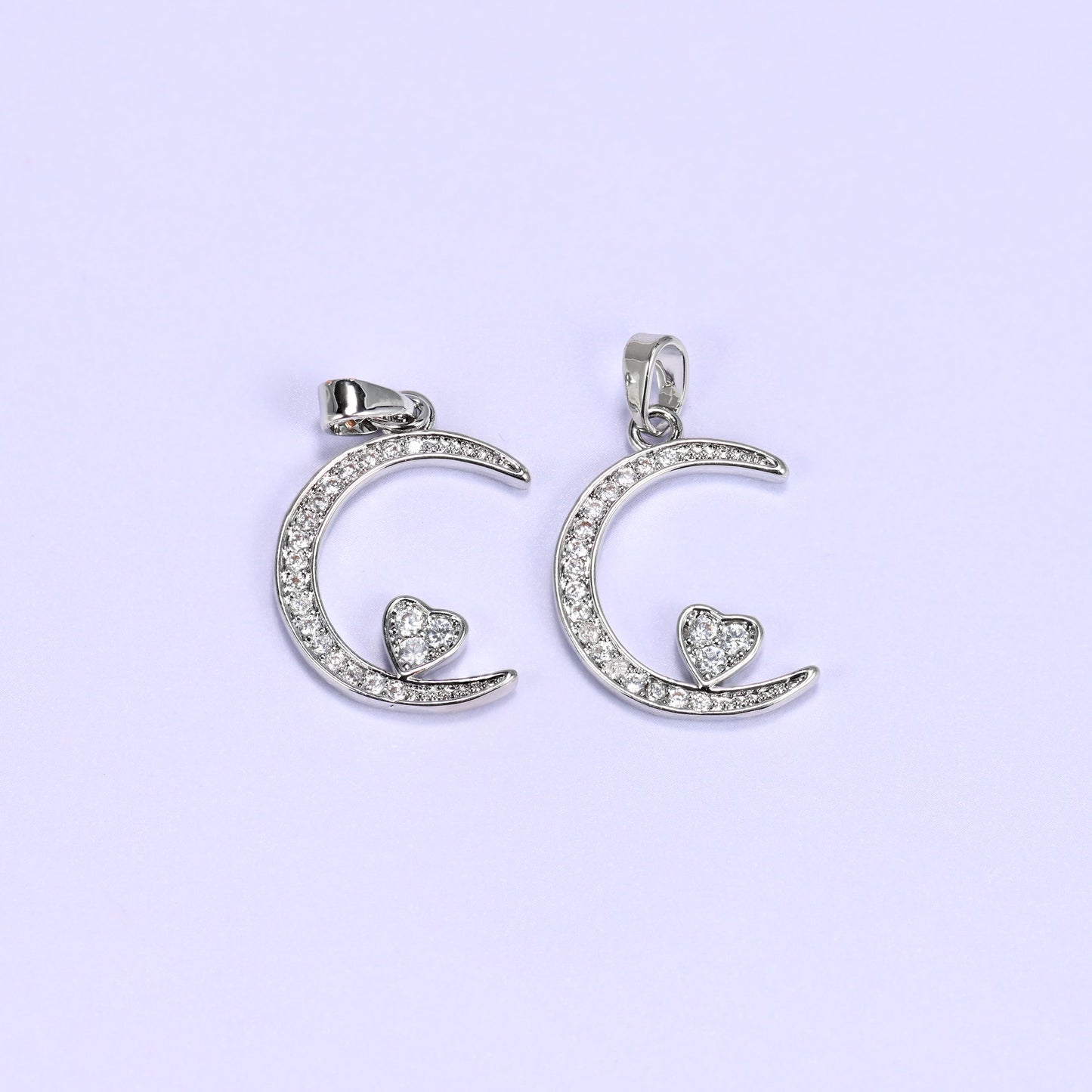 Silver moon heart zirconia charms paired side by side, both crescent pendants set with clear pave stones.