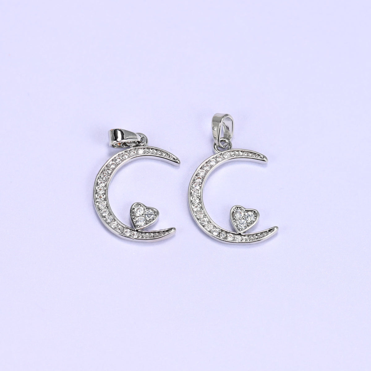 Silver moon heart zirconia charms paired side by side, both crescent pendants set with clear pave stones.