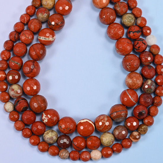 Flower red jasper faceted round beads photographed at an angle to show natural luster.