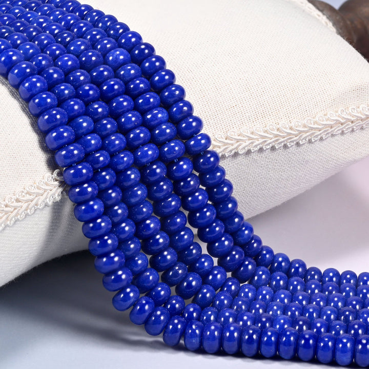 Dark Blue dyed jade gemstone rondelle beads draped in rows, deep saturated blue discs with a glossy polish