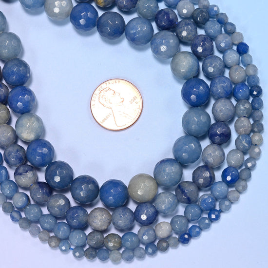Denim and steel blue mottled with pale grey and slate, cut into faceted rounds that pick up light in flecks rather than one broad highlight. Polished glossy