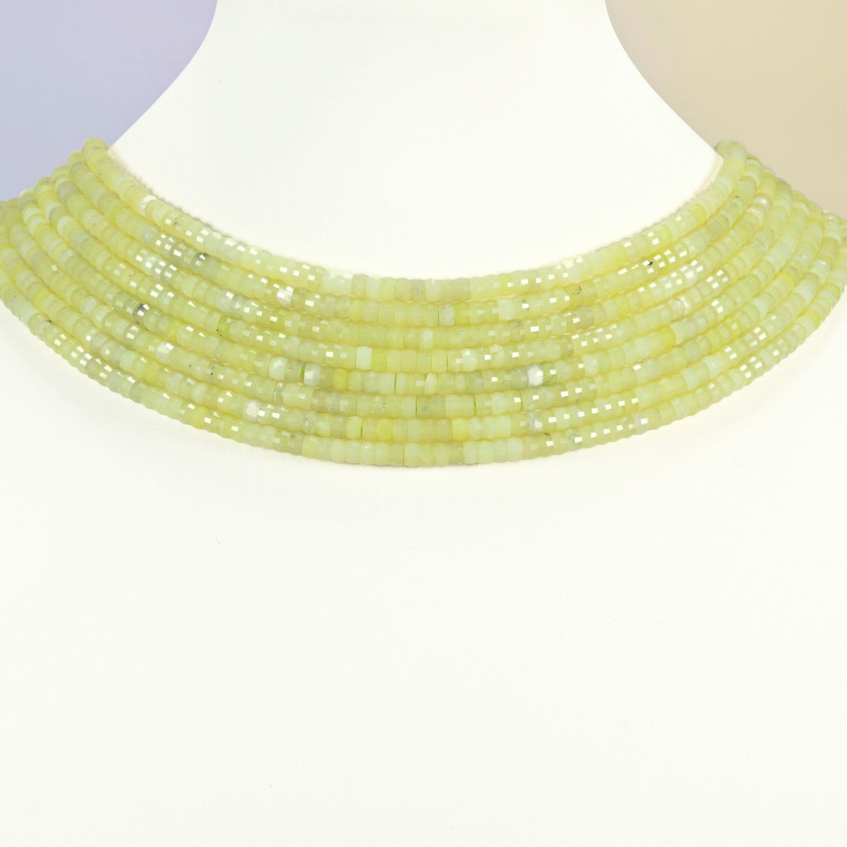Lemon Jade faceted heishi disc strands arranged as a layered collar on a white display bust, yellow-green beads across the neck