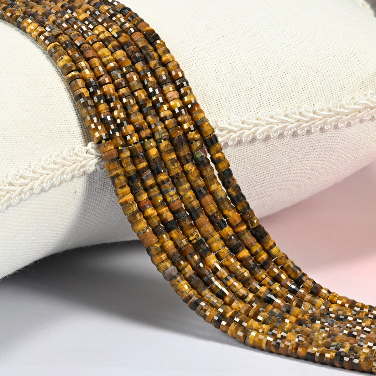 Tiger eye faceted heishi disc beads 2x4mm, several strands draped over a white cushion