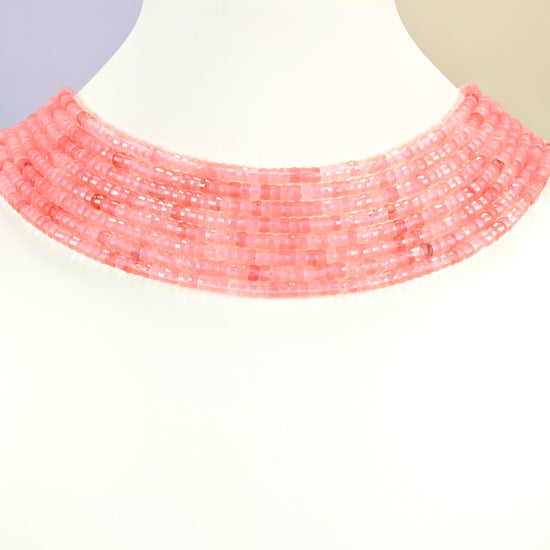 Melon quartz faceted heishi disc strands arranged as a layered collar on a white display bust, pink beads across the neck