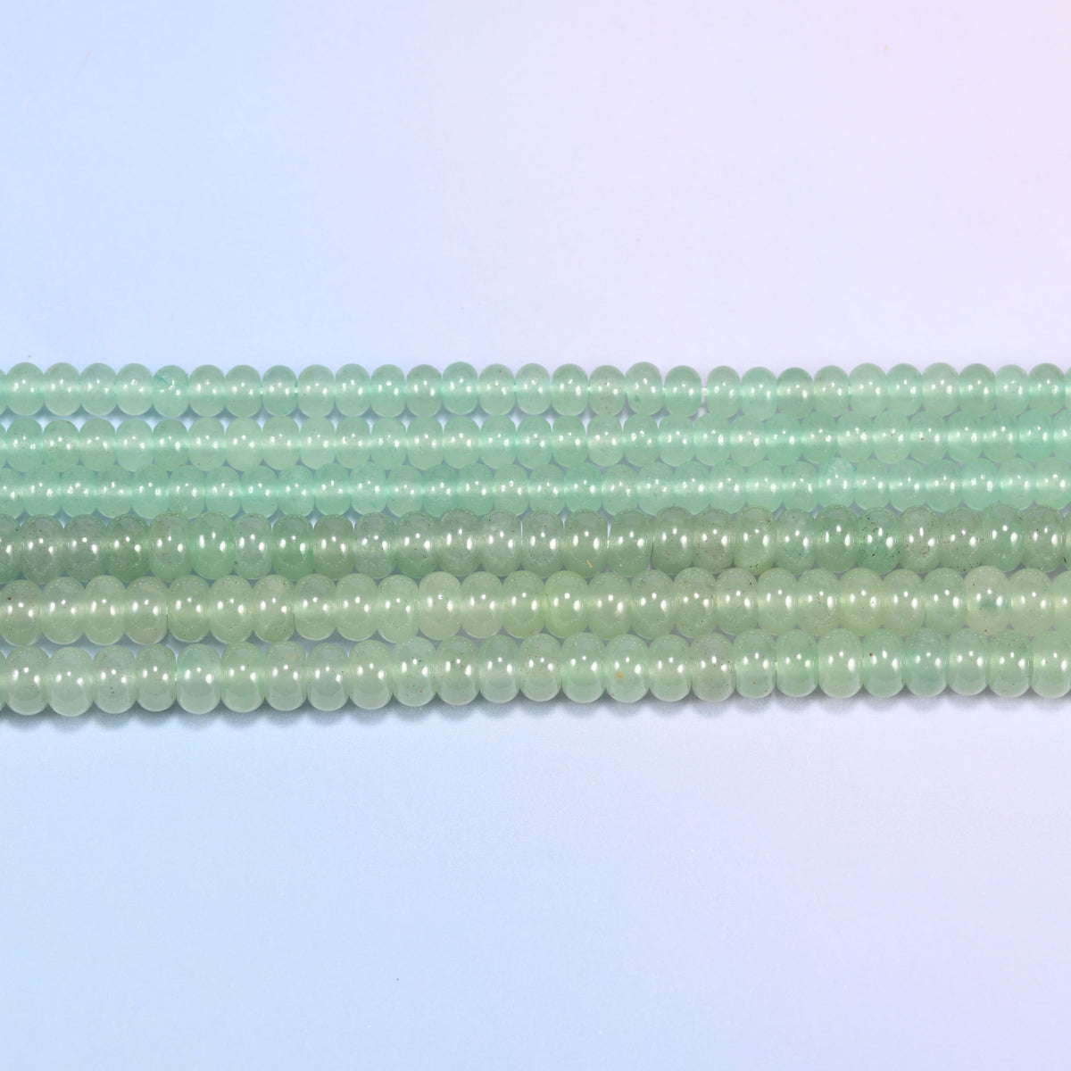 Green Aventurine gemstone rondelle beads in straight rows, showing the flat disc profile and centre drilling