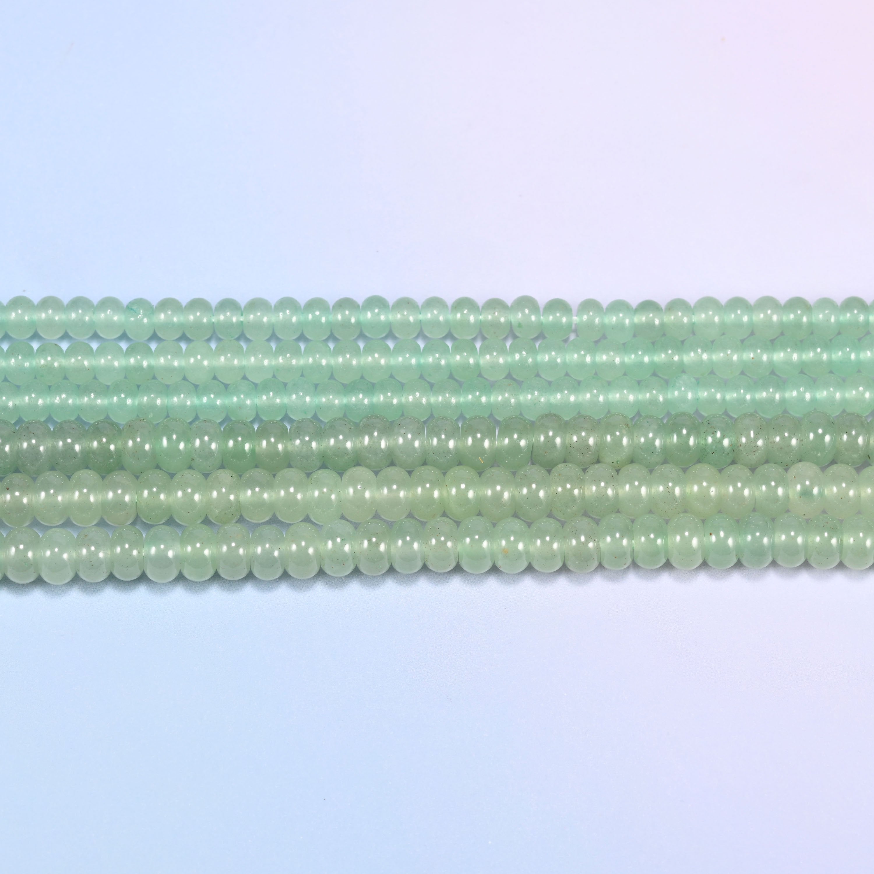 Green Aventurine gemstone rondelle beads in straight rows, showing the flat disc profile and centre drilling