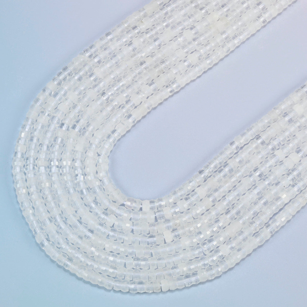 Clear quartz faceted heishi disc beads in several strands curved into a wide U, clear and milky white stone