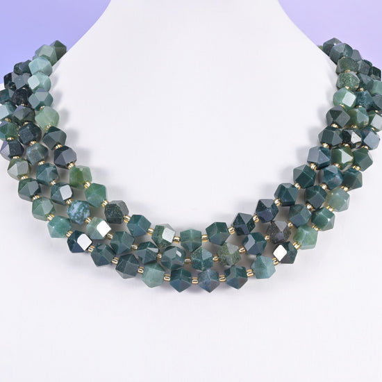 Faceted 8 sides diamond rhombus beads in moss agate on a white neck display, three strands layered.