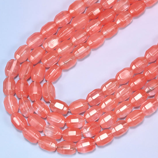 Close-up of a circular coil of coral pink faceted glass barrel beads on a light background.