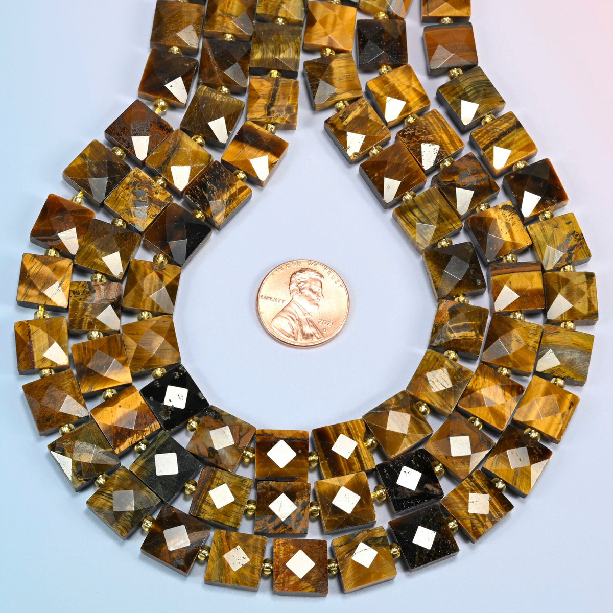 Natural tiger eye faceted flat square strands formed into a teardrop loop around a US penny for scale