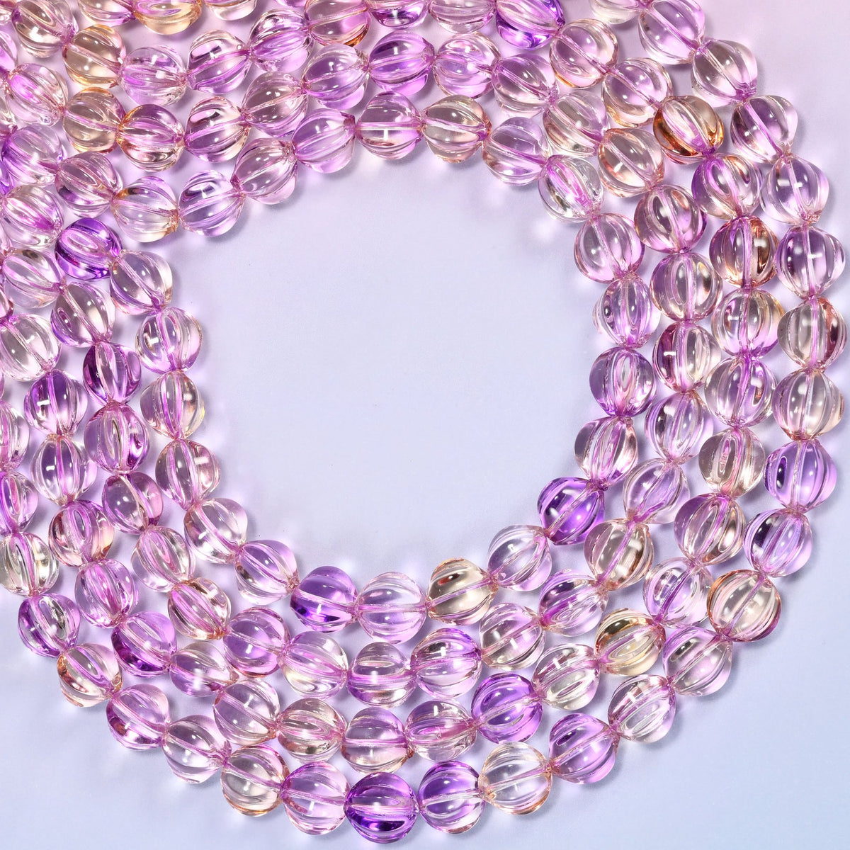 Clear purple gold pumpkin glass beads looped into one wide open ring, the strands running off both sides of the frame.