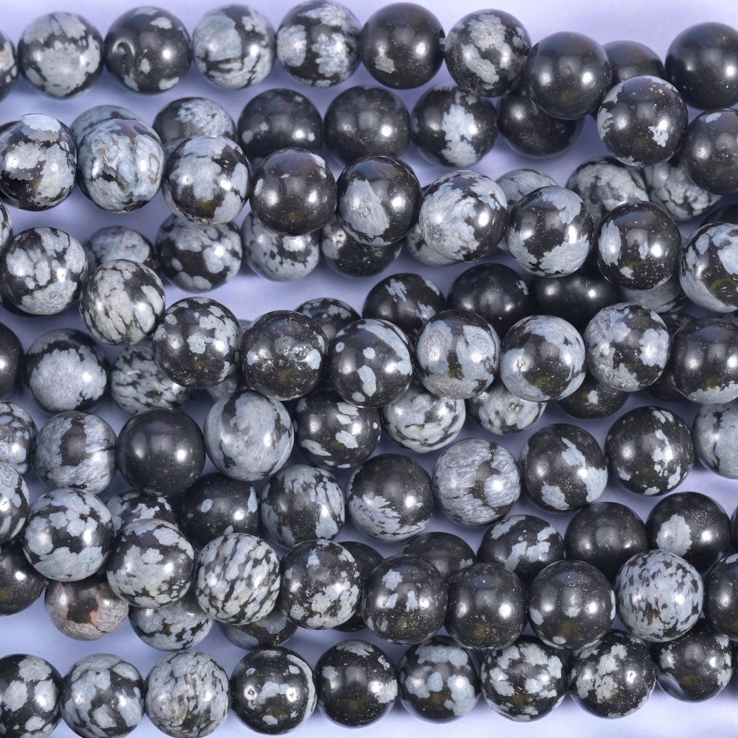 Charcoal and near-black rounds crazed with pale grey and white markings that break the surface like frost on glass
