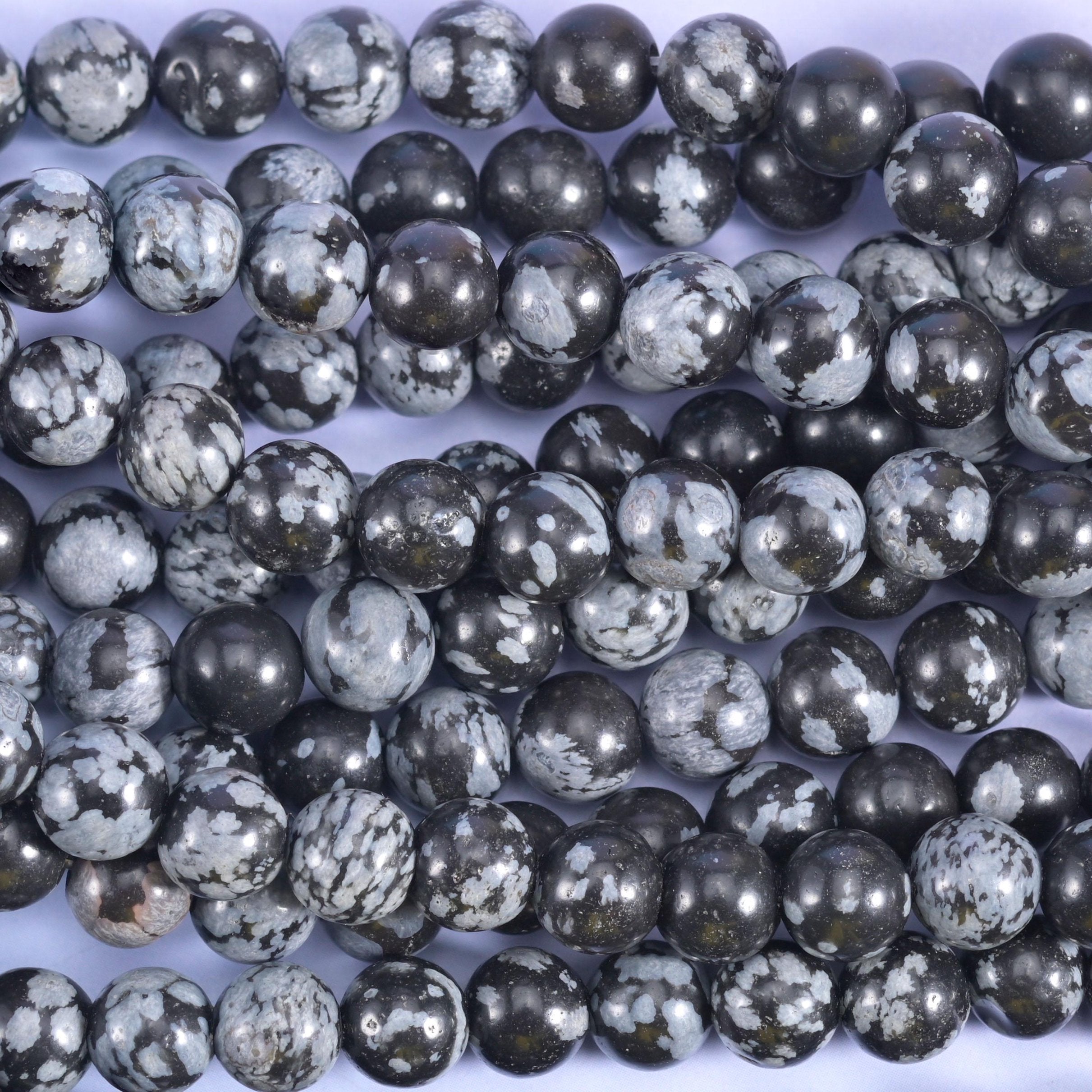 Charcoal and near-black rounds crazed with pale grey and white markings that break the surface like frost on glass