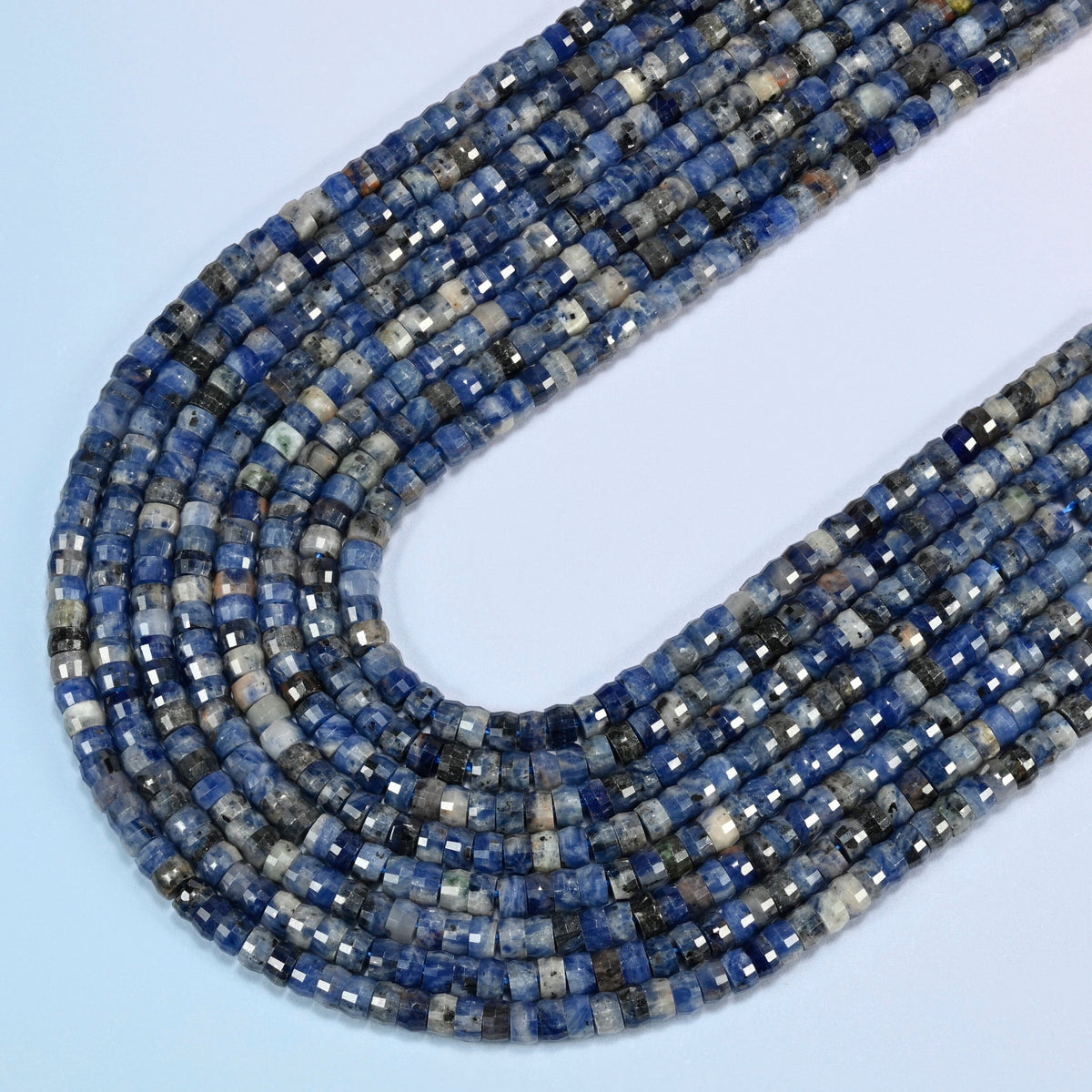 Sodalite faceted heishi disc beads in several strands curved into a wide U, deep blue stone with white patches