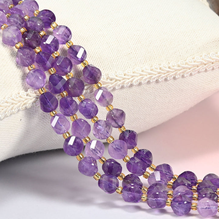 Amethyst faceted spiral twist beads against a white cushion, soft purple stone with gold seed spacers.