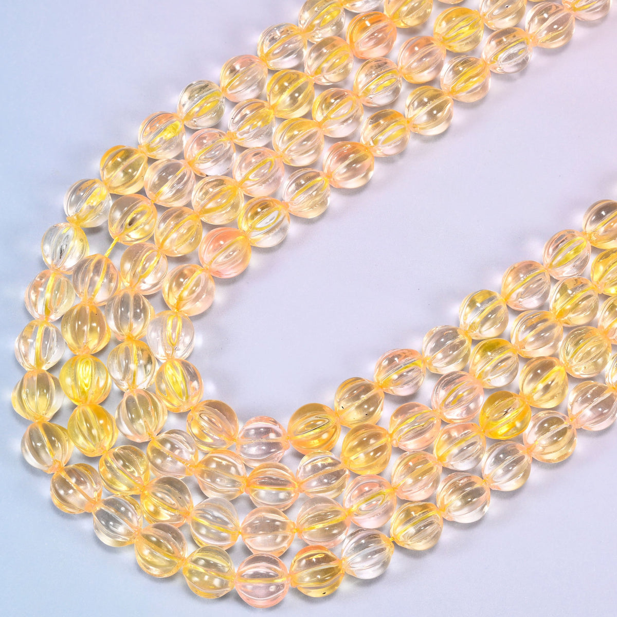 Yellow clear pumpkin glass beads, several strands laid in a wide sweeping curve across the frame.