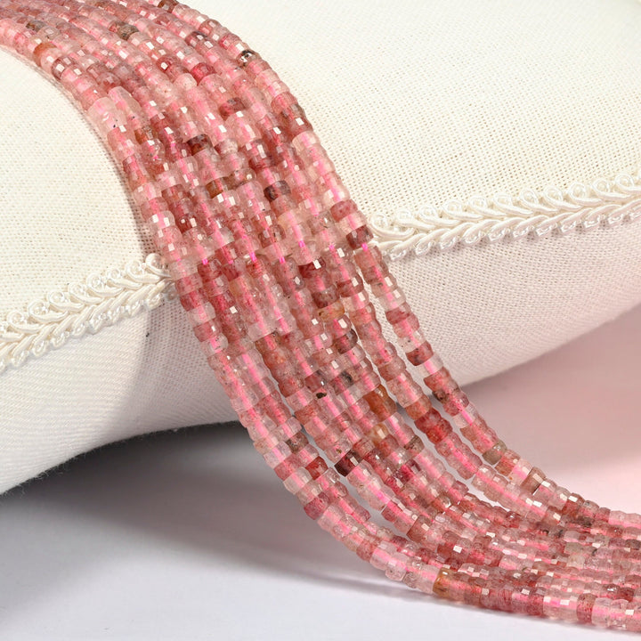 Strawberry quartz faceted heishi disc beads 2x4mm, several strands draped over a white cushion
