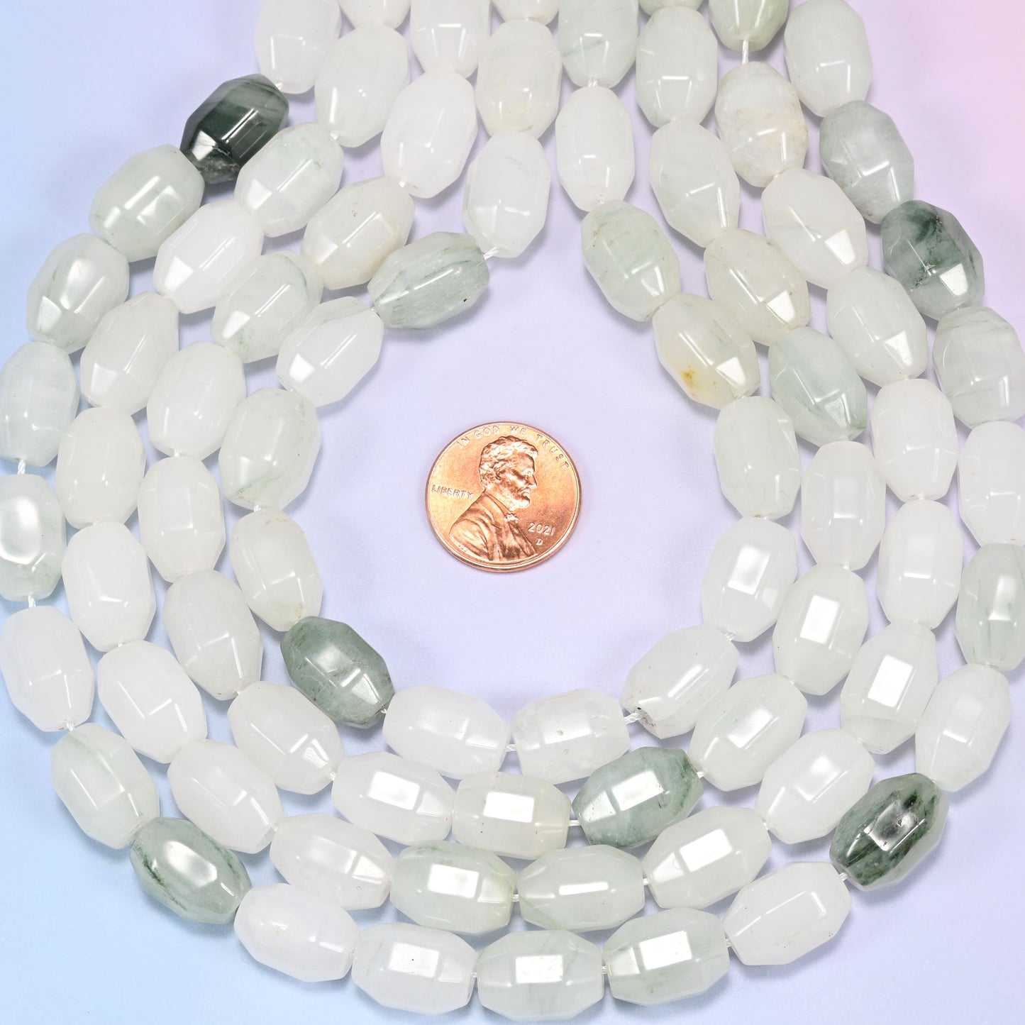 Wide circular coil of Tianshan Jade faceted barrel beads on a light lavender and pink gradient background, showing the full wreath.