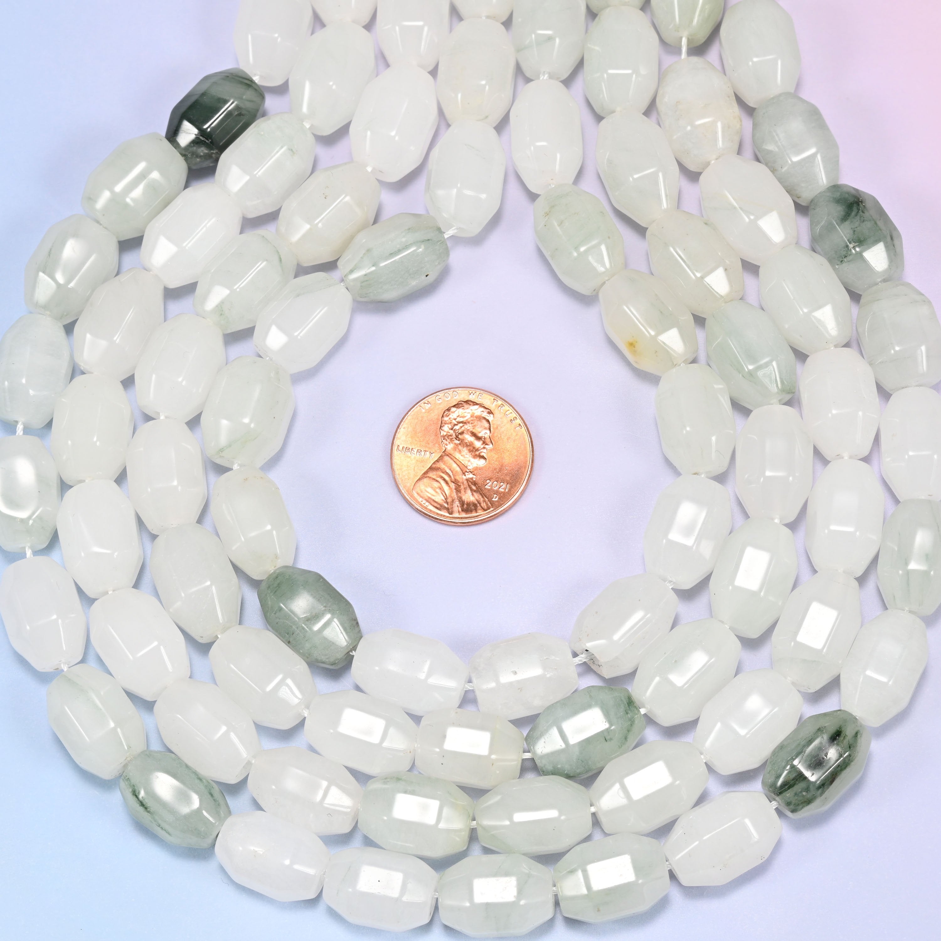 Wide circular coil of Tianshan Jade faceted barrel beads on a light lavender and pink gradient background, showing the full wreath.