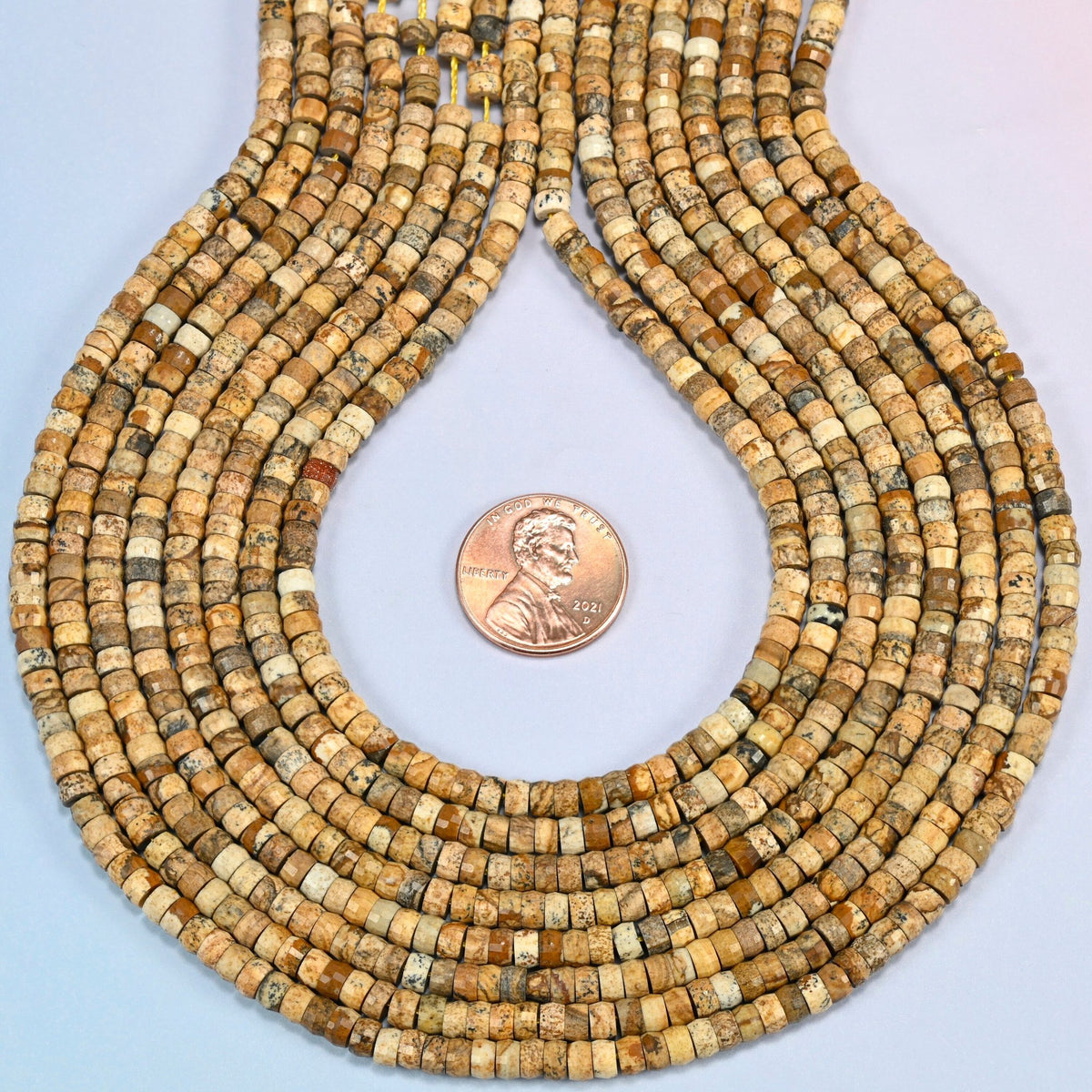 Picture jasper faceted heishi disc strands formed into a teardrop loop around a US penny for scale