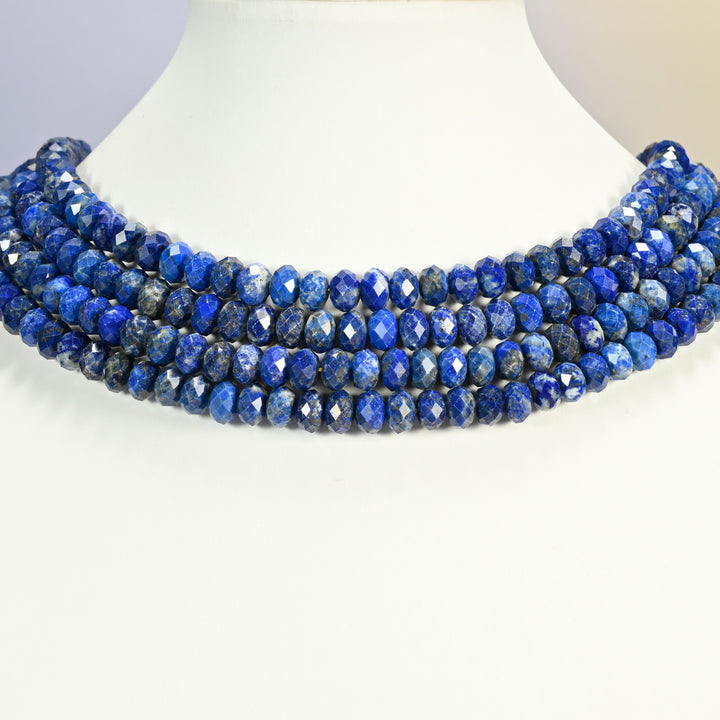 Lapis lazuli faceted rondelle strands arranged as a layered collar on a white display bust, royal blue beads across the neck