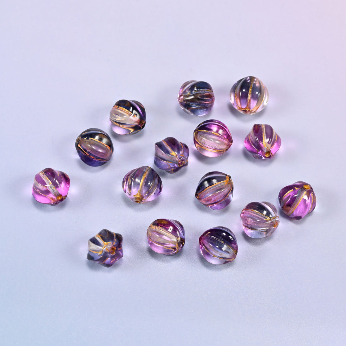 A scattered group of loose 8mm pink blue gold pumpkin glass beads, showing the melon ribs and the drill holes.