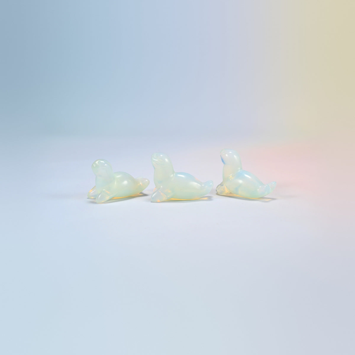 Three opalite sea lion crystal carvings, 1.5 inch, glowing milky white man-made glass