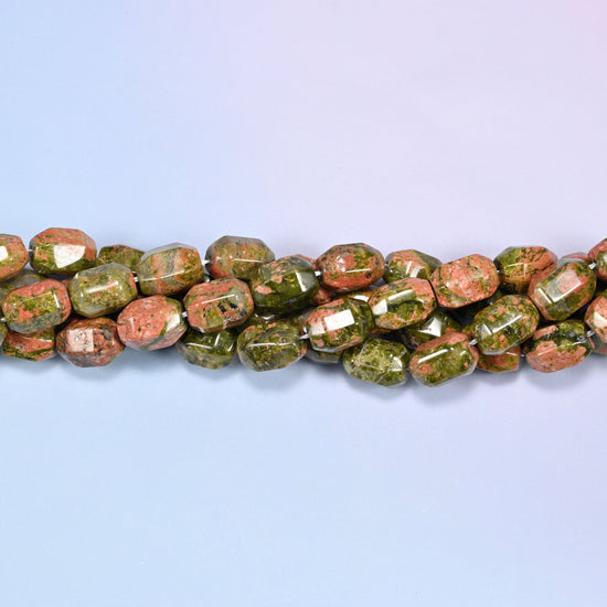 Close-up of a dense circular coil of faceted Unakite barrel beads, showing the octagonal facet cuts.